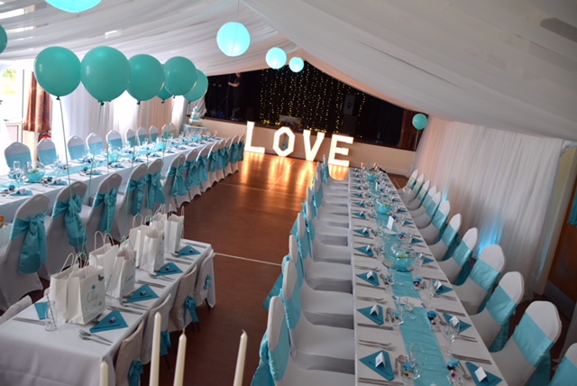 Hall decorated for a wedding reception with a LOVE light installation by the stage